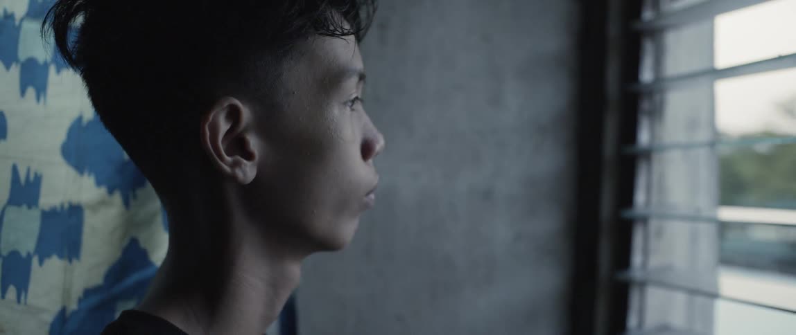 Man stares out of a window through the blinds
