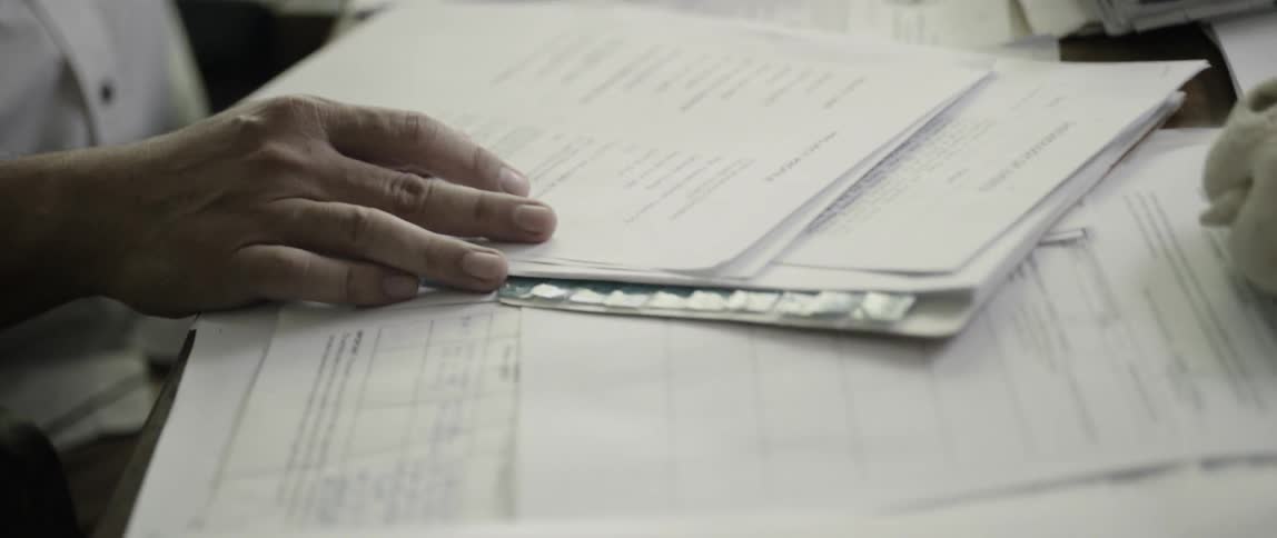 A man touches the papers spread out on his desk