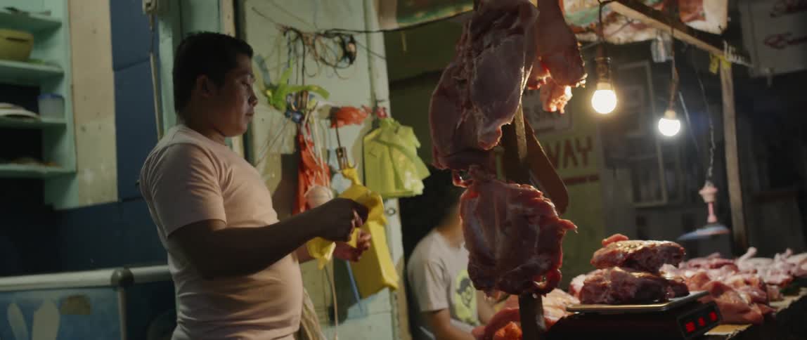 Man chops meat with a cleaver in the butcher shop