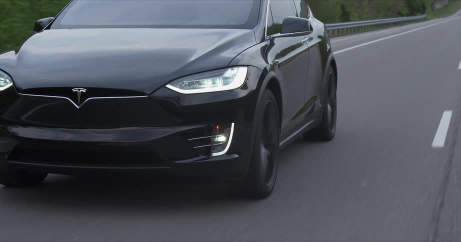 A tesla car rides down the road