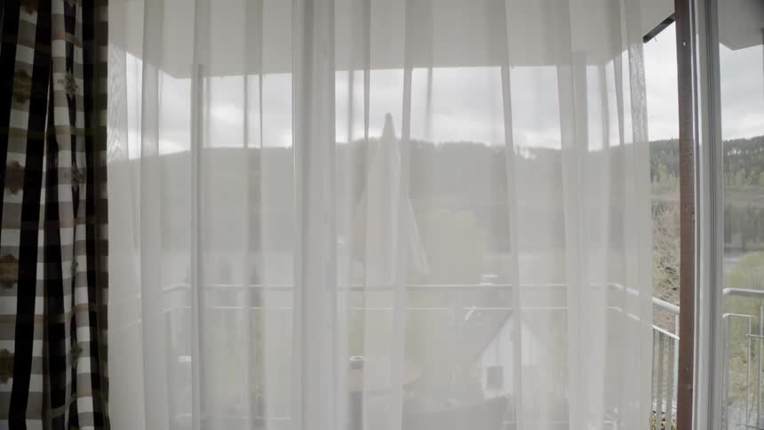 White curtains sway lightly at a window