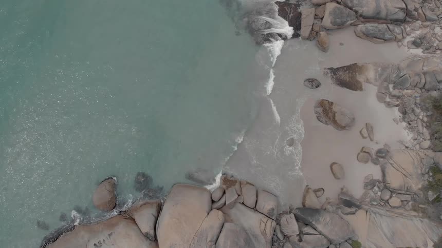 Water rolls into shore towards the rocks