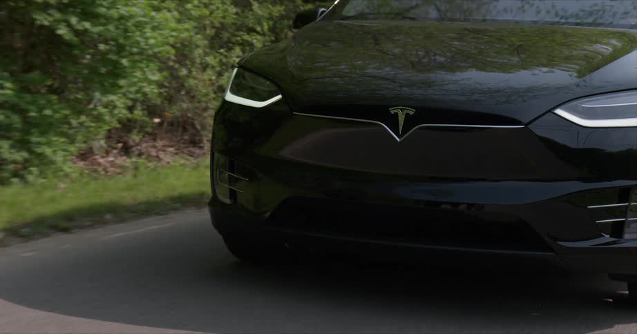 A tesla car rides down the road