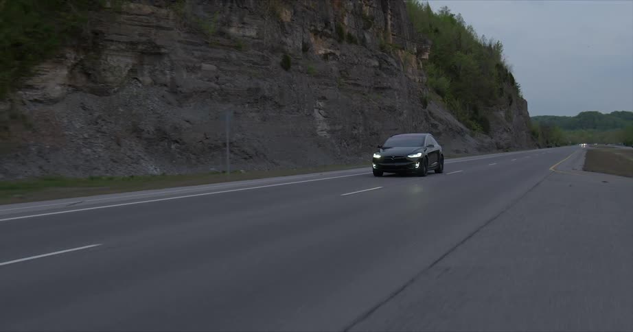 A tesla car rides down the road