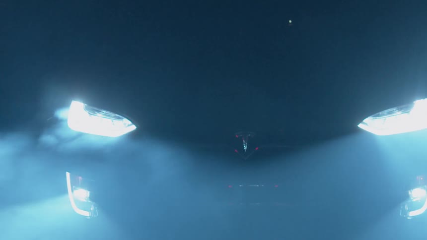 A car's headlights shine in the mist