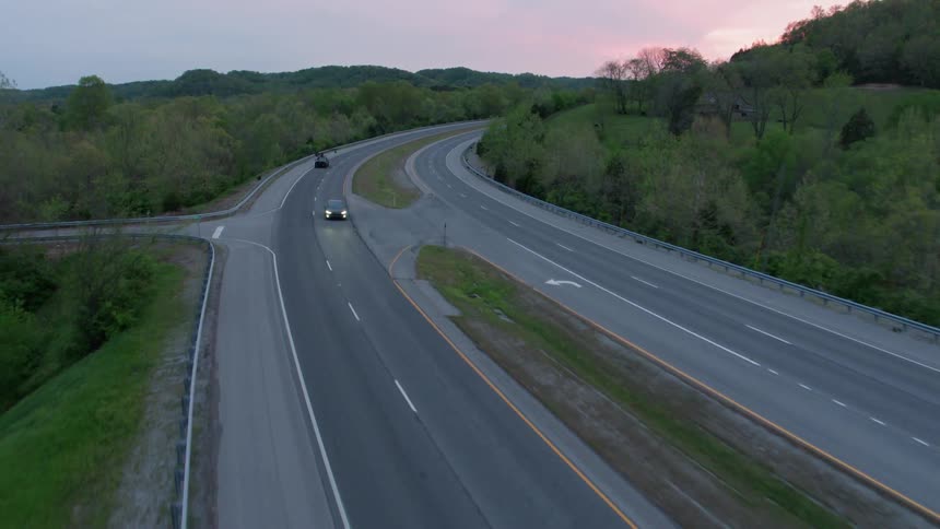 Cars drive on a rural road at sunset