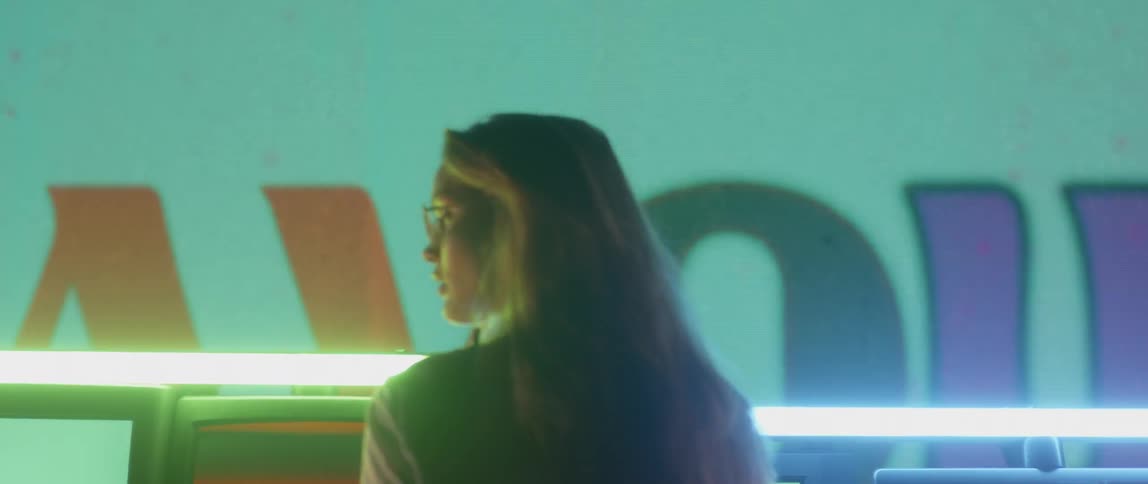 A woman stands by screens flashing vibrant colors