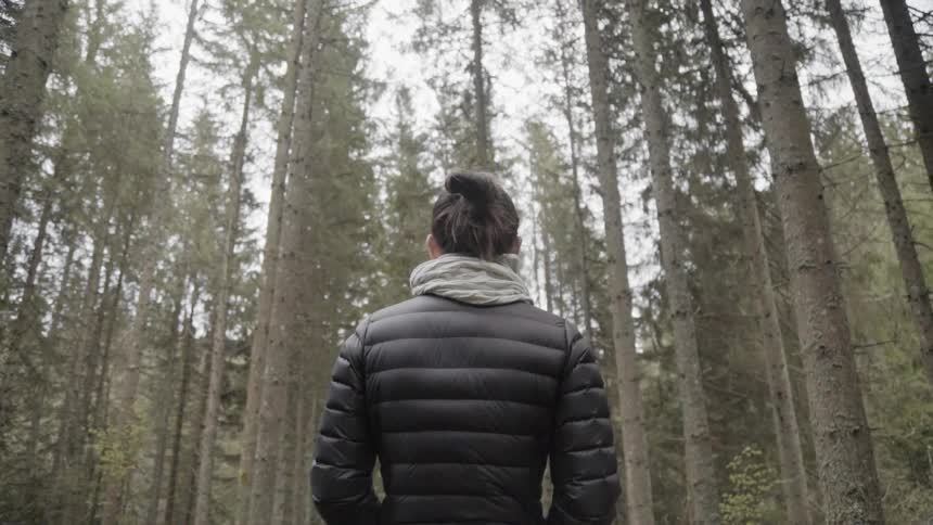 A woman stands in front of the large forest