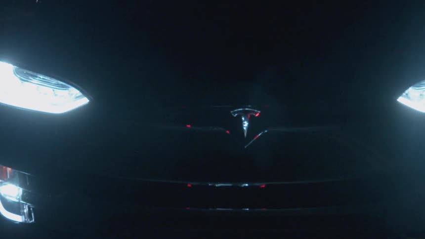 The car is traveling on the road at night
