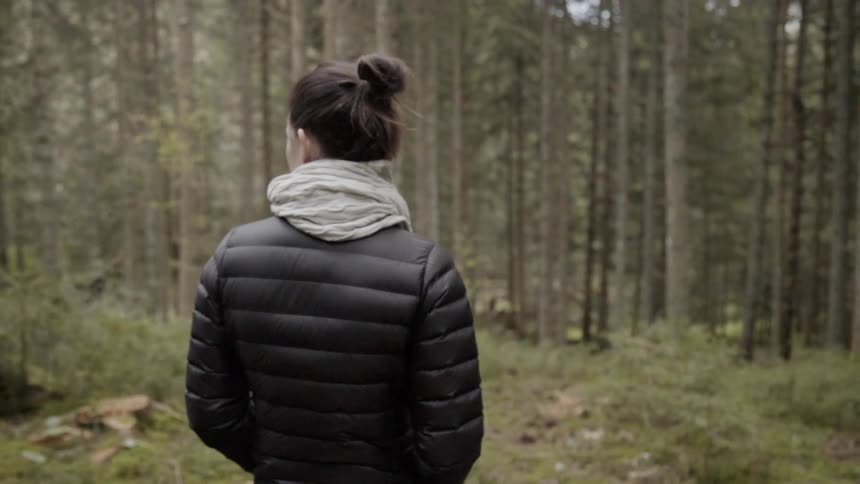 Woman wearing a coat stands in a forest