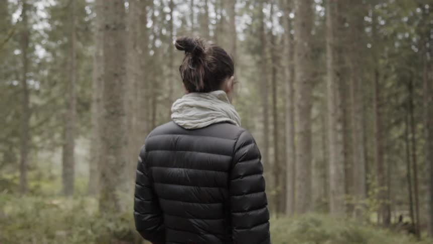 Woman is standing still outside in forest area