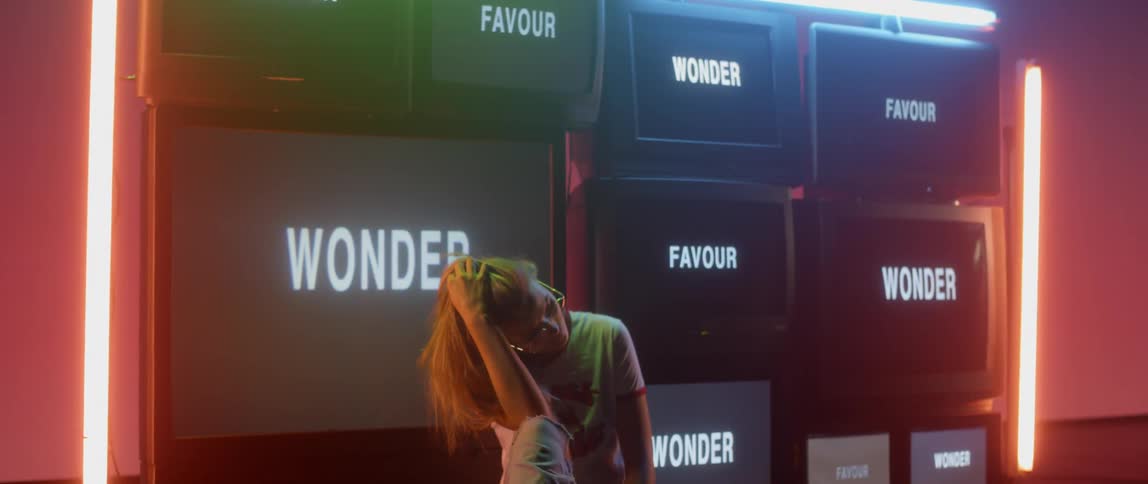 Woman stands in front of stacked televisions
