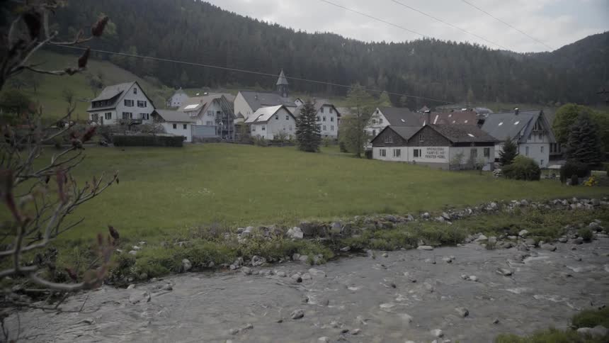 A river is flowing past a village on a cloudy day