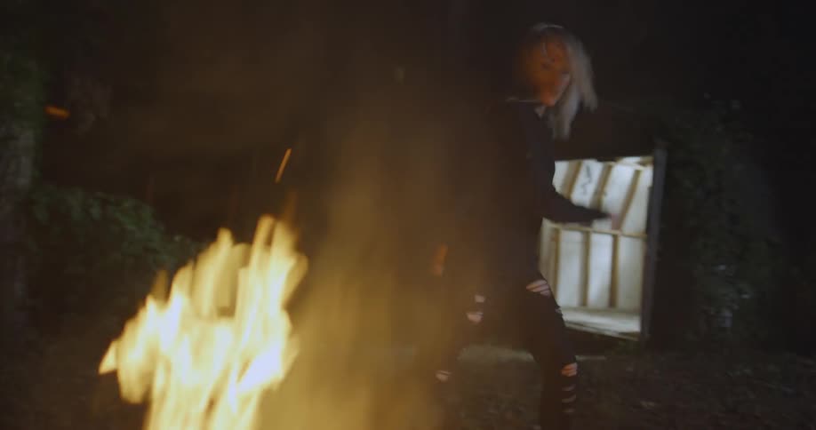 Woman dances next to a bonfire