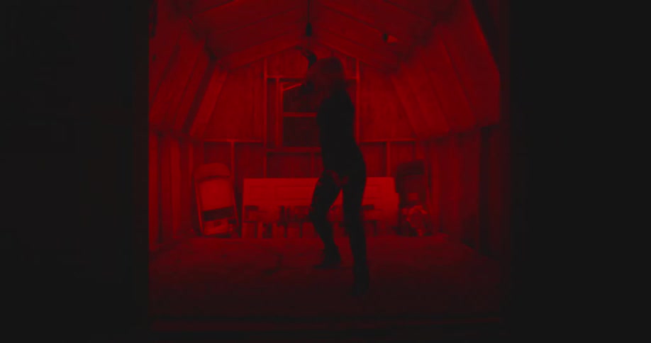 Woman performs dance moves in a room illuminated with a red light
