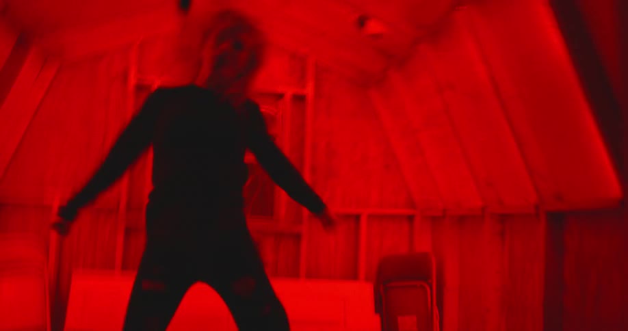 Woman dances in a small room illuminated by red light