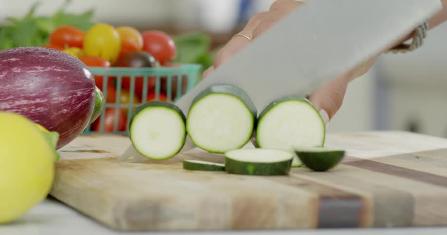 Woman slices a zucchini with a large knife