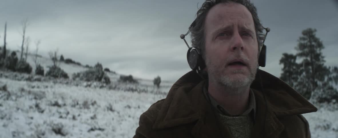 A man standing in a snowy field with headphones