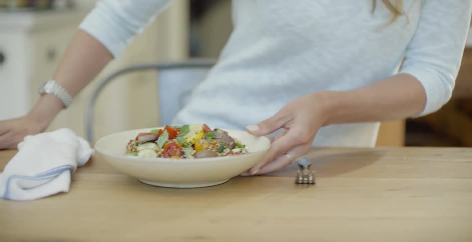 A woman sits down with a meal