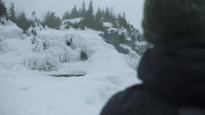A man looks out over the ice covered shore