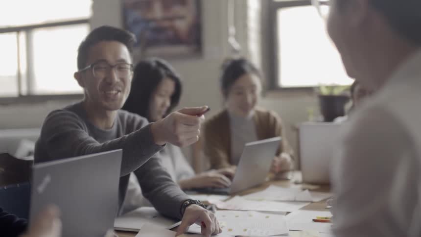 A man laughs at a table with many workers