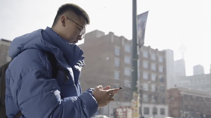 Man uses his phone on a city sidewalk