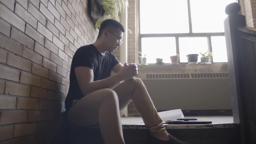 Man reads a paper while sitting on steps