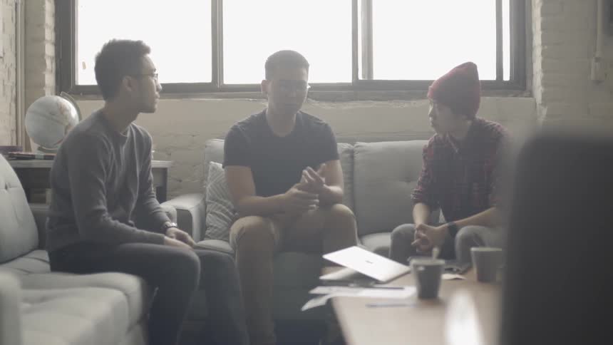 Group of people sit talking in a living room