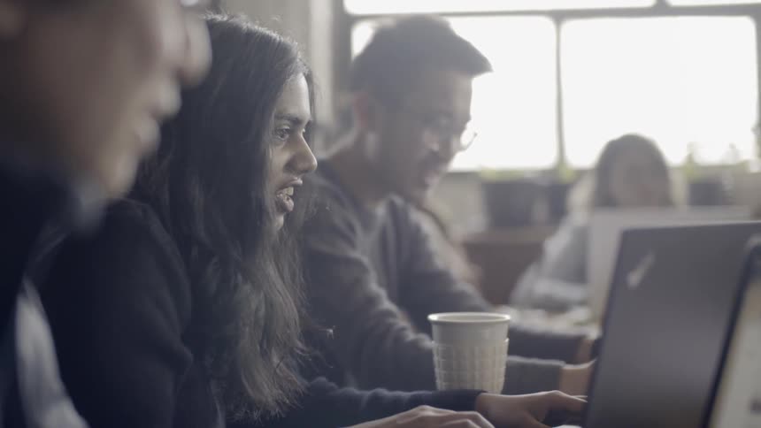 Employees work on laptops in an office