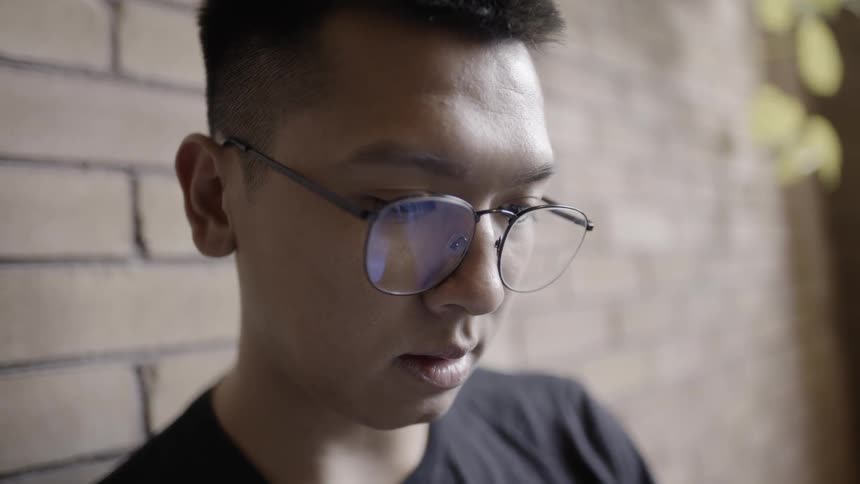 Man wearing glasses looks down with light reflecting off his glasses