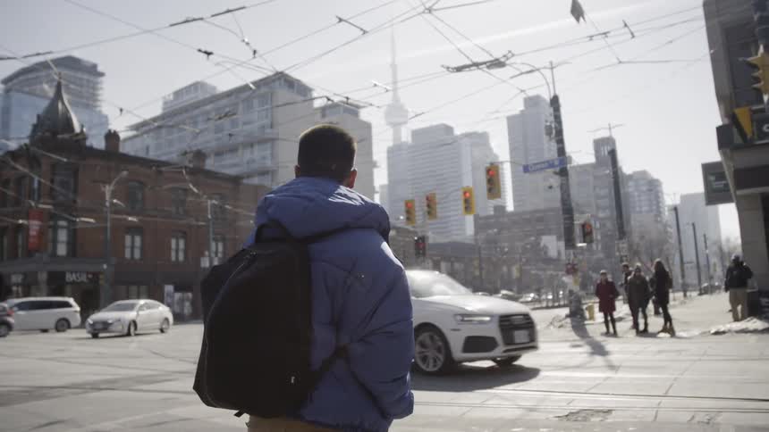 Man with a backpack watches the traffic go by