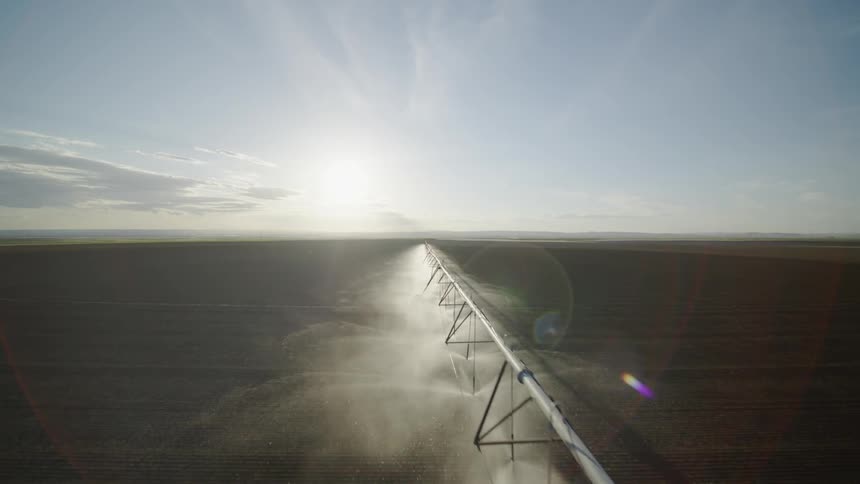 Pullback flyover of a center pivot irrigation boom working along a freshly plowed field