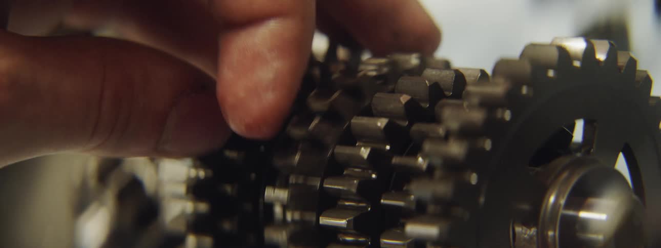 Hand turns a gear among several gears