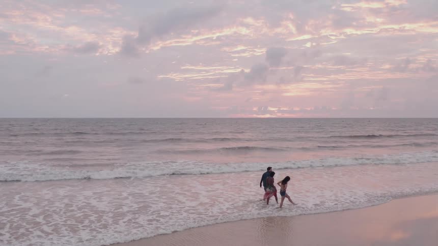 Three people walk outside on the beach on a cloudy day