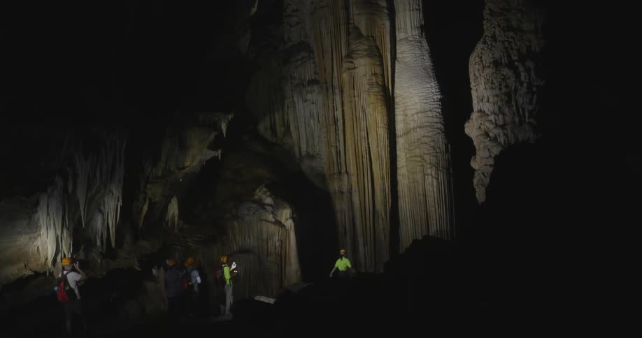 People walk through a large dark cave