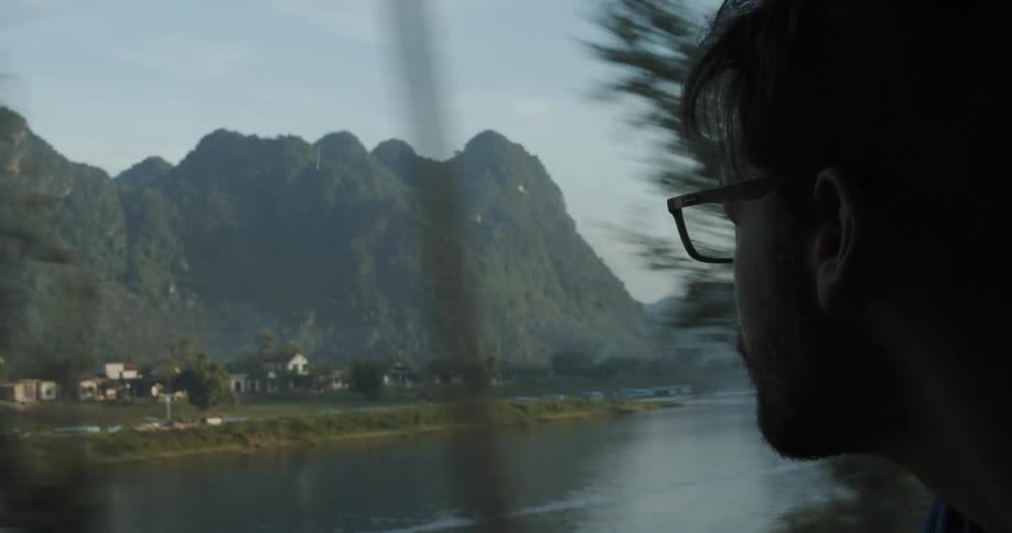 Man looks at a mountain town while riding on a train