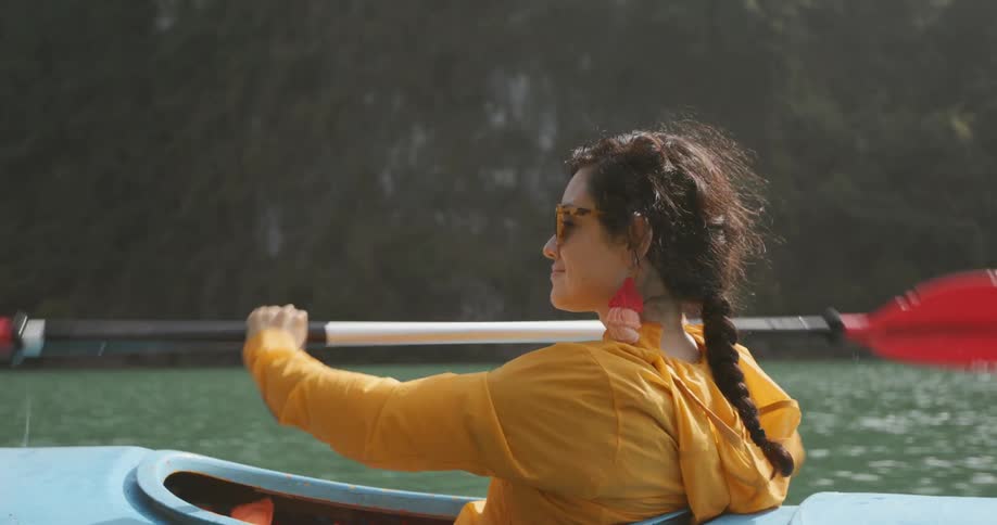 A woman smiles as she rows a canoe