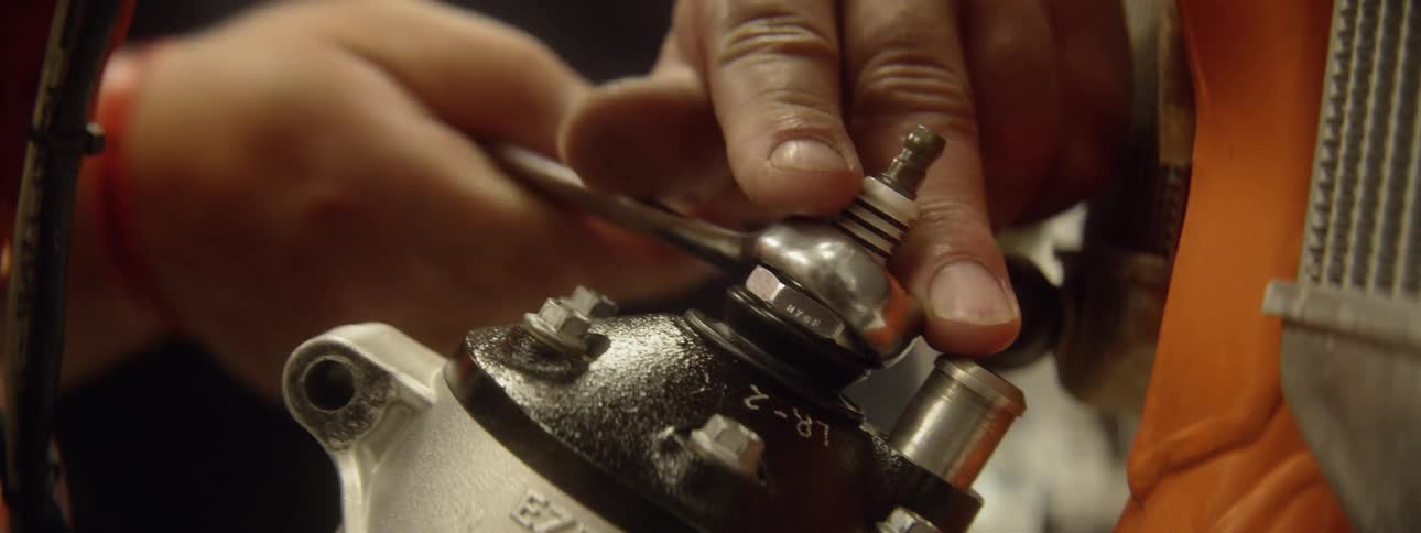 A mechanic is working on an engine in daylight