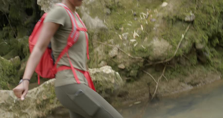 A woman is jumping into a pool of water and wading across it in daylight