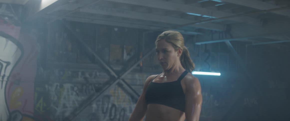 Woman does deadlifts with a large barbell in a warehouse