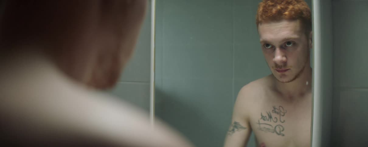 Man looks in a bathroom mirror