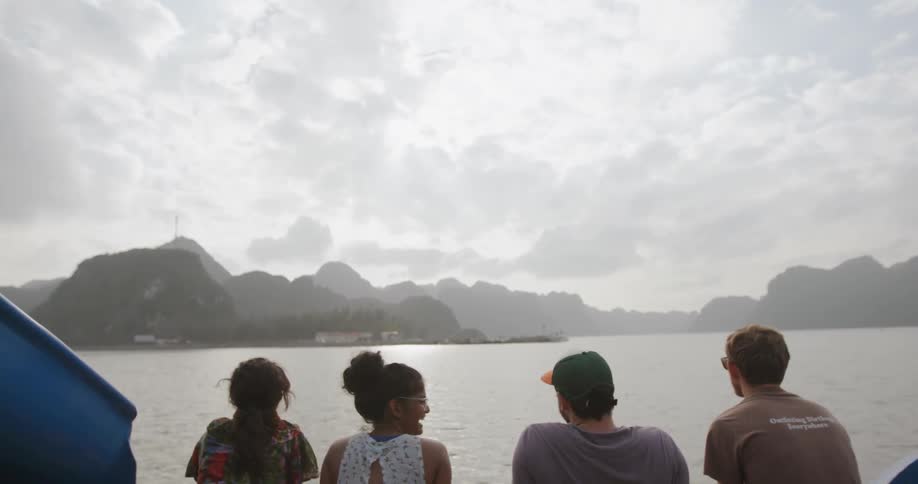 Group of people are talking and laughing on boat on cloudy day