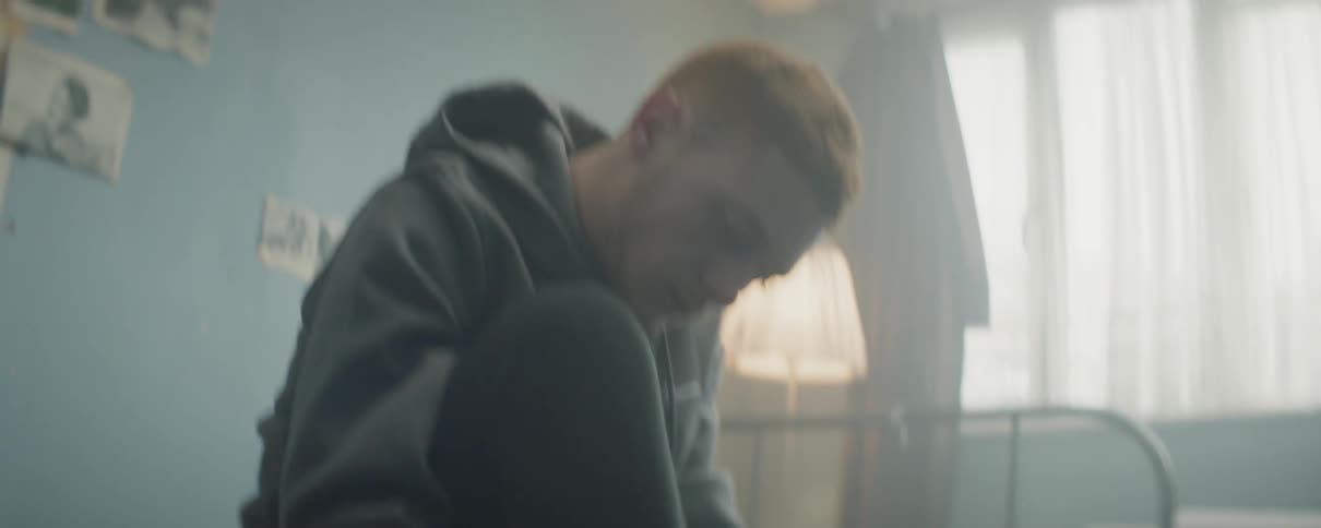 Man sitting on bed is tying his shoes