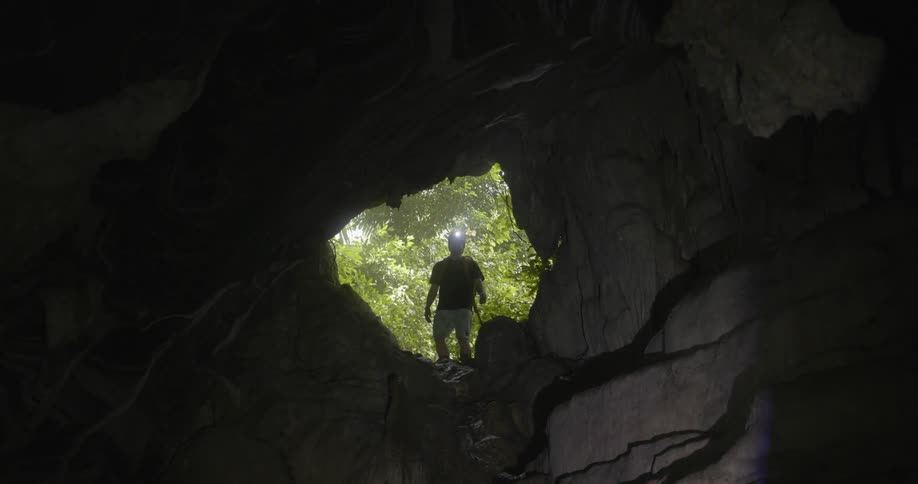 A man climbs up to enter the cave from above