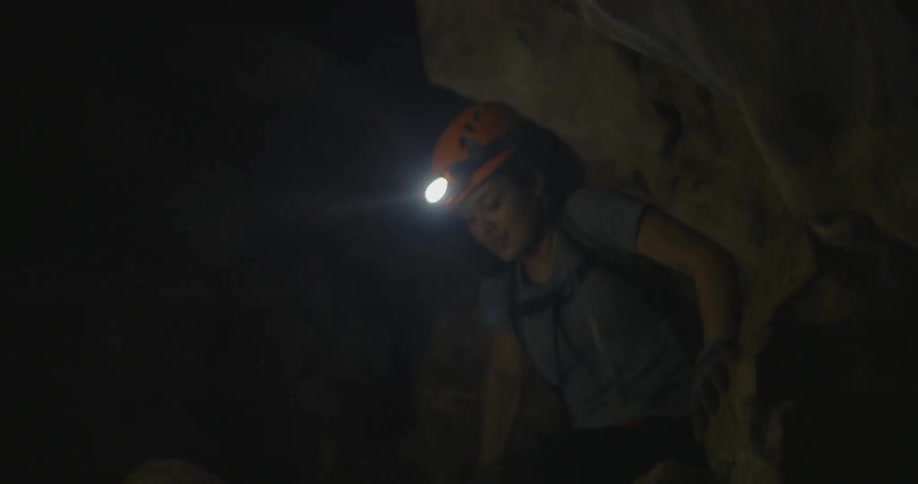 Person wearing a headlamp climbs in a rocky cave