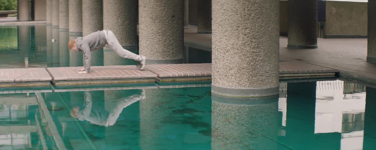 Man is doing burpees outside by a pool