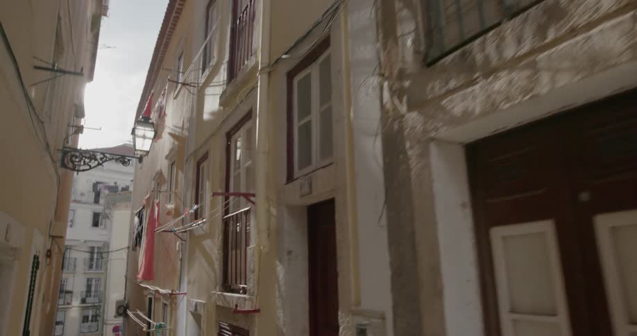 Laundry hangs from lines outside of windows in a narrow alley