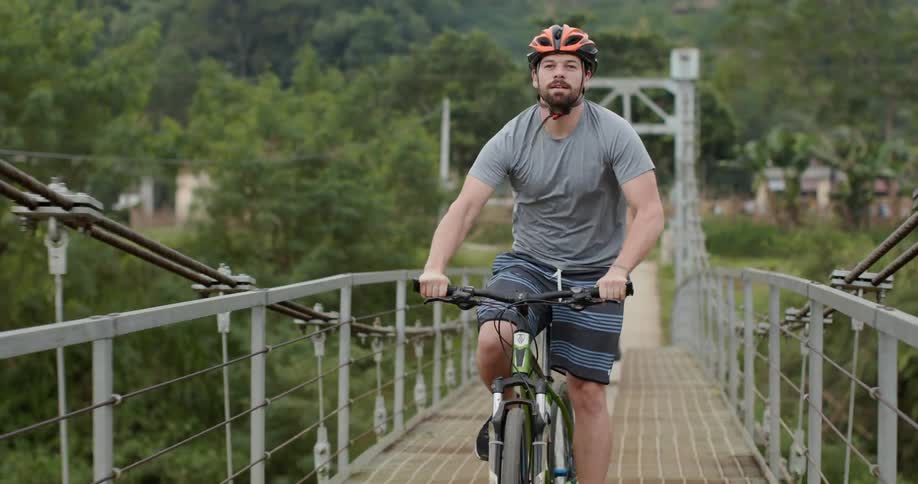 A man rides his bike over the bridge