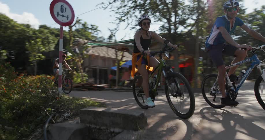 Bicyclists ride their bikes on the road under the bright sun