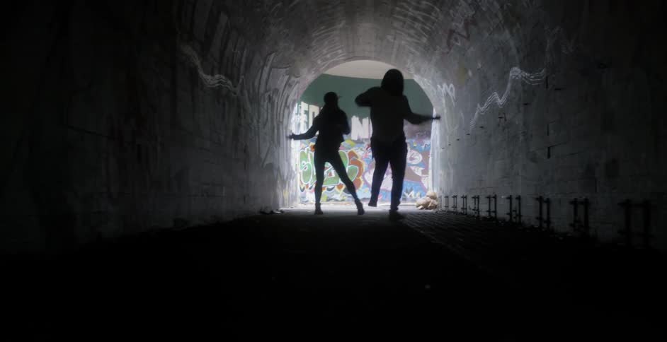 Two women dance in a tunnel